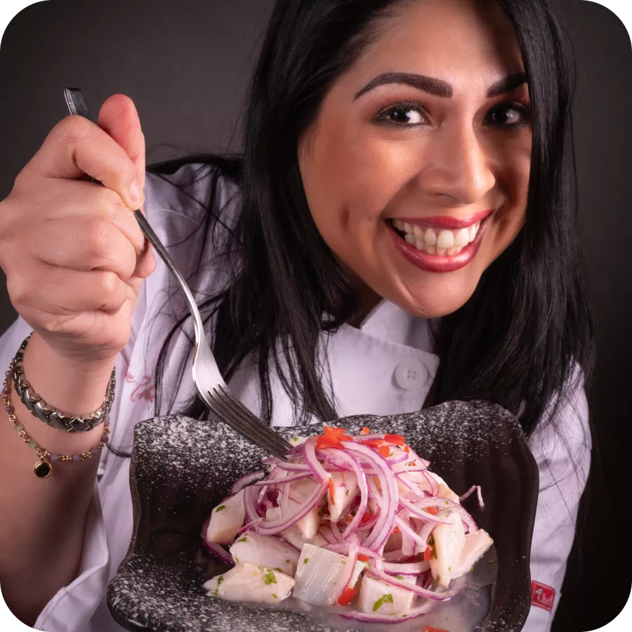 Chef Magaly Ponce smiling and holding a plate of fresh ceviche, with onions, cilantro, and fish.